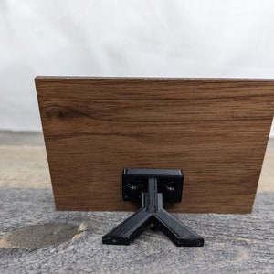May include: A wooden sign with a black stand. The sign is brown with a wood grain pattern.