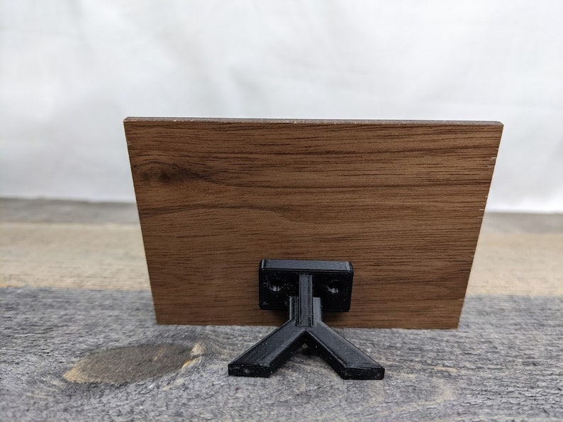 May include: A wooden sign with a black stand. The sign is brown with a wood grain pattern.
