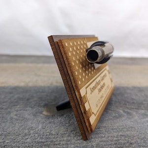 A wooden plaque with a US flag design and a brass shell casing mounted on top.