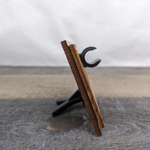A wooden picture frame with a black stand.