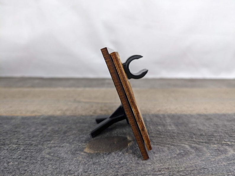 A wooden picture frame with a black stand.