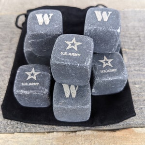 May include: A black velvet bag filled with six gray stone whiskey chilling cubes.  The cubes are engraved with the letters "W" and the words "U.S. ARMY" with a star.