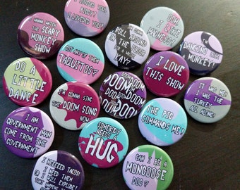May include: A collection of 14 round buttons with various colorful designs and text. The buttons feature phrases like "I love this show", "Do a little dance", "The pig commands me", "I'm gonna sing the doom song now", "Somebody needs a hug", and "I need tacos".