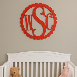 May include: A red wooden monogram with the letters WSC hangs above a white crib. The crib contains a teddy bear and a pink unicorn plush toy. The crib has a gray cloud-patterned sheet.