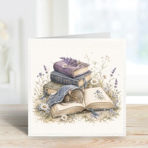May include: A square greetings card featuring a watercolour illustration of a small brown mouse sleeping under a blue blanket on an open book. A stack of two closed books sits behind it, surrounded by sprigs of purple lavender and white daisies.