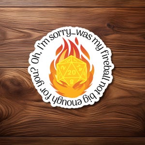 May include: A white sticker featuring a yellow 20-sided die engulfed in orange flames. The text "Oh, I'm sorry... was my fireball not big enough for you?" is arranged around the die in a circular fashion.