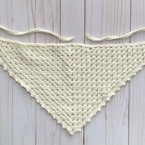 May include: A white crocheted triangular scarf with a scalloped edge.
