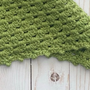 May include: A close-up of a green crocheted fabric with a scalloped edge.