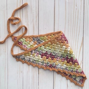 May include: A crocheted triangular scarf with a scalloped edge in shades of brown, green, and pink. The scarf has a long brown cord attached to it.