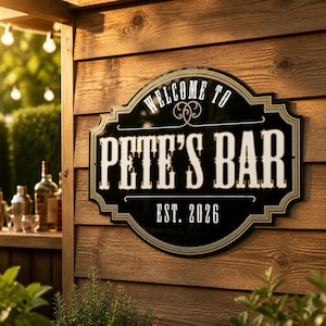 May include: A black, decorative, wall-mounted sign with a gold border and white lettering. The text reads "WELCOME TO PETE'S BAR" with "EST. 2026" below. The sign has a scalloped, rectangular shape with rounded corners and ornate flourishes.