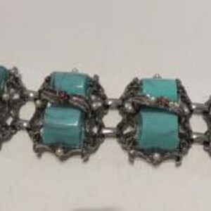 May include: A turquoise and silver bracelet with a chain link design and large turquoise stones. The stones are set in silver and have a textured surface. The bracelet has a clasp closure.
