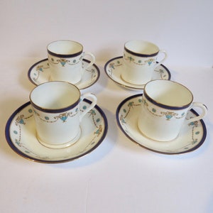May include: Set of four white porcelain teacups and saucers with blue and gold trim. The cups and saucers feature a delicate floral design with a gold accent.