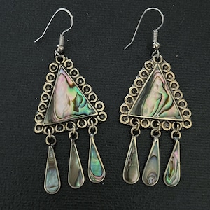 May include: A pair of dangle earrings featuring triangular frames with scalloped edges, inlaid with iridescent abalone shell. Each earring has three dangling teardrop-shaped charms, also inlaid with abalone, suspended from the base of the triangle.