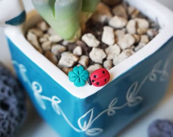 Miniature ladybug and four-leaf clover stud earrings in polymer clay.