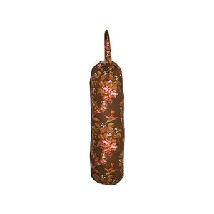 May include: A brown fabric bag dispenser with a floral pattern featuring red roses and birds. The bag dispenser has a white handle.
