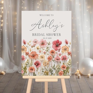 May include: Welcome to Ashley's Bridal Shower sign with a watercolor floral design in shades of pink and orange. The date of the shower is March 27, 2025.