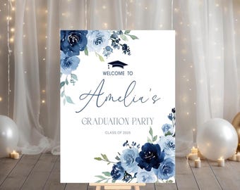 May include: A white welcome sign with blue watercolor flowers and greenery. The sign reads "Welcome to Amelia's Graduation Party Class of 2025".