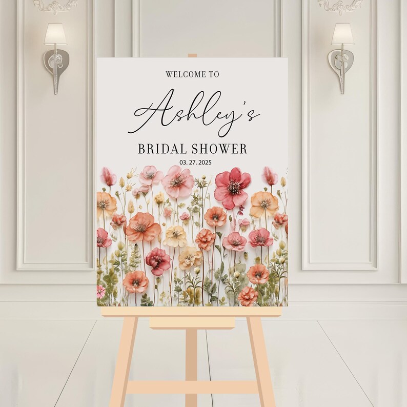 May include: Welcome to Ashley's Bridal Shower sign with a floral design featuring pink and orange flowers on a white background. The date of the shower is 03.27.2025.
