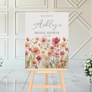 May include: Welcome to Ashley's Bridal Shower sign with a watercolor floral design featuring pink, peach, and yellow flowers on a white background.