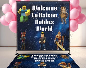 May include: A backdrop and floor mat set with the text "Welcome to Kaison Roblox World" and Roblox character illustrations. The backdrop is dark blue with a starry background, and pink balloons are on the left side.