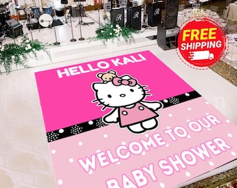 Op de afbeelding: Een rechthoekige vloersticker met een felroze bovengedeelte met de tekst HELLO KALI en een wit Hello Kitty-figuurtje in een roze jurk. Het onderste gedeelte is lichtroze met witte stippen en de tekst WELCOME TO OUR BABY SHOWER.