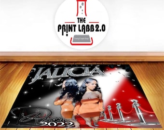 May include: A black and red custom backdrop with the name "JALICIA" in silver glitter letters. The backdrop features two women in orange dresses standing on a red carpet with a spotlight shining on them. The text "Prom 2022" is at the bottom of the backdrop.