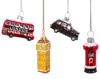 May include: Four glass ornaments featuring iconic London landmarks: a red double-decker bus with "LONDON" written on the side, a black taxi cab, a red telephone booth, and Big Ben.