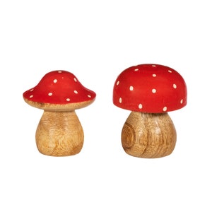 May include: Two wooden mushroom figurines with red and white polka dot caps. The mushrooms are different sizes and are made of natural wood.