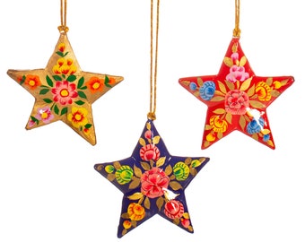 May include: Three star-shaped ornaments with floral designs. The stars are painted in gold, red, and blue with colorful flowers and leaves.