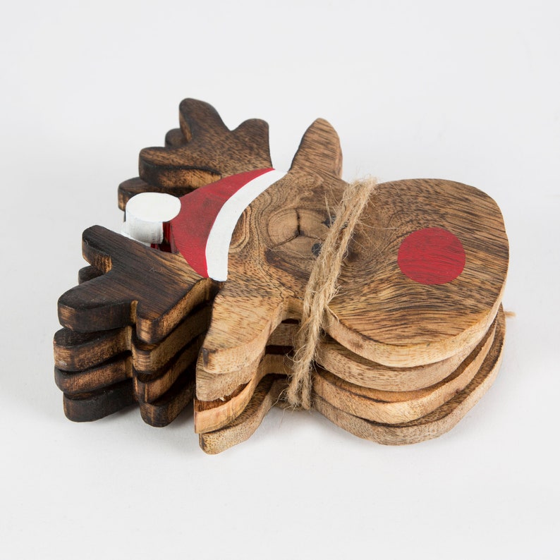 Pu&ograve; includere: Set di quattro sottobicchieri di legno a forma di renna con un cappello di Babbo Natale dipinto di rosso e bianco e un naso rosso. I sottobicchieri sono legati insieme con uno spago.