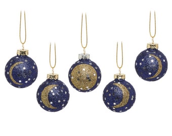 May include: Five navy blue Christmas baubles with gold glitter crescent moons and stars. Each bauble has a gold string for hanging. The baubles have a glittery texture and a metallic gold cap.