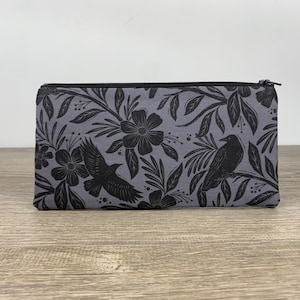 May include: A gray zippered pouch with a black and white floral pattern featuring ravens and leaves.