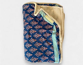 May include: A blue and pink patterned throw blanket with a tan fleece backing and a teal and gold trim.