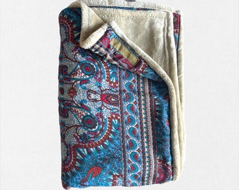 May include: A blue and red paisley patterned throw blanket with a cream coloured fleece backing.