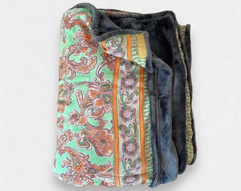May include: A green and orange paisley patterned throw blanket with a dark grey fleece backing.