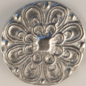 May include: A silver button with a raised, ornate floral design. The button has a smooth, rounded surface and a slightly raised center.