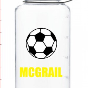 Puede incluir: Botella de agua de pl&aacute;stico transparente con tapa negra y un gr&aacute;fico de bal&oacute;n de f&uacute;tbol en blanco y negro. El nombre "MCGRAIL" est&aacute; impreso en amarillo debajo del gr&aacute;fico.