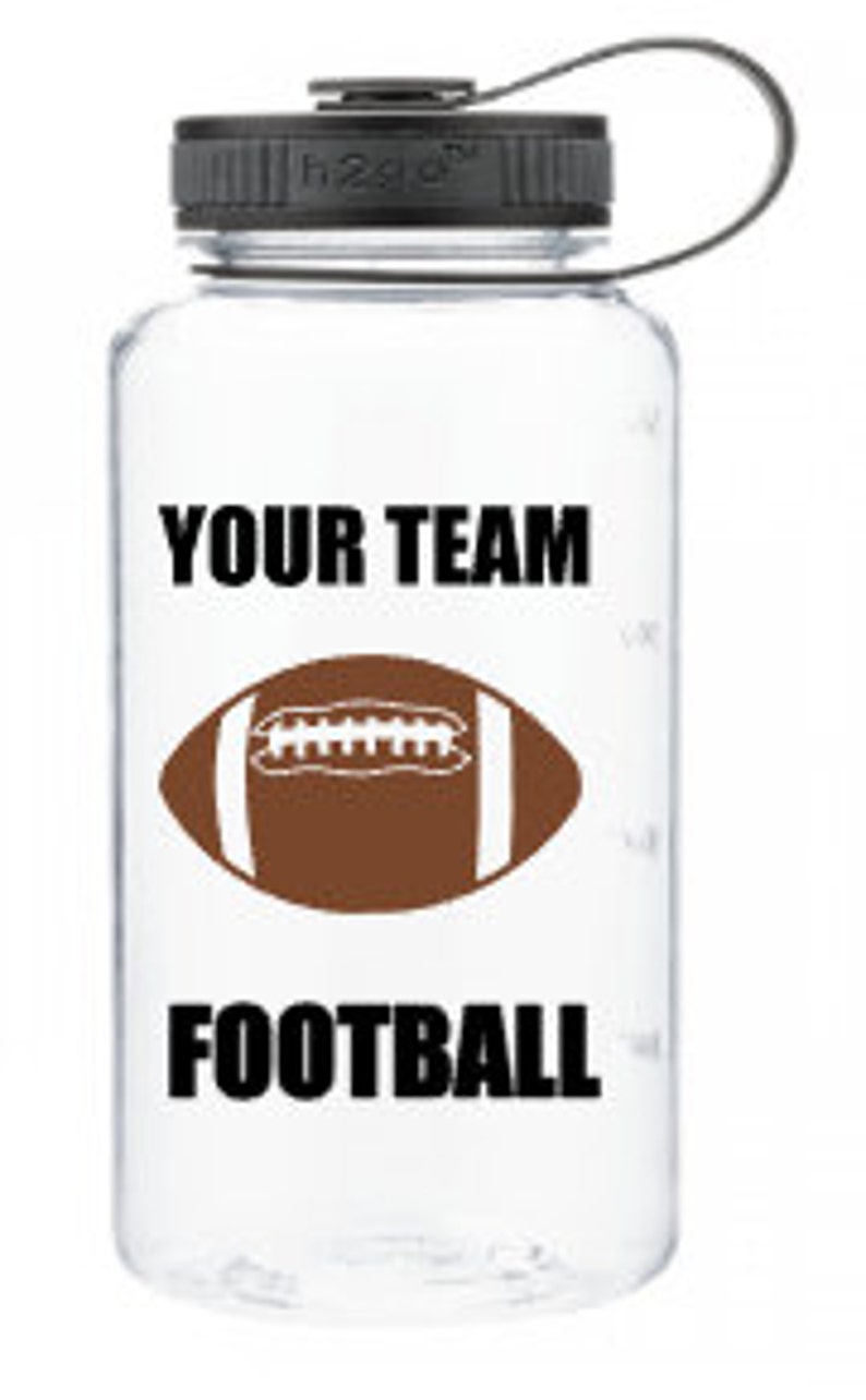 Puede incluir: Botella de agua de pl&aacute;stico transparente con tapa negra y asa de transporte negra. La botella tiene un gr&aacute;fico de f&uacute;tbol blanco y el texto "YOUR TEAM FOOTBALL".