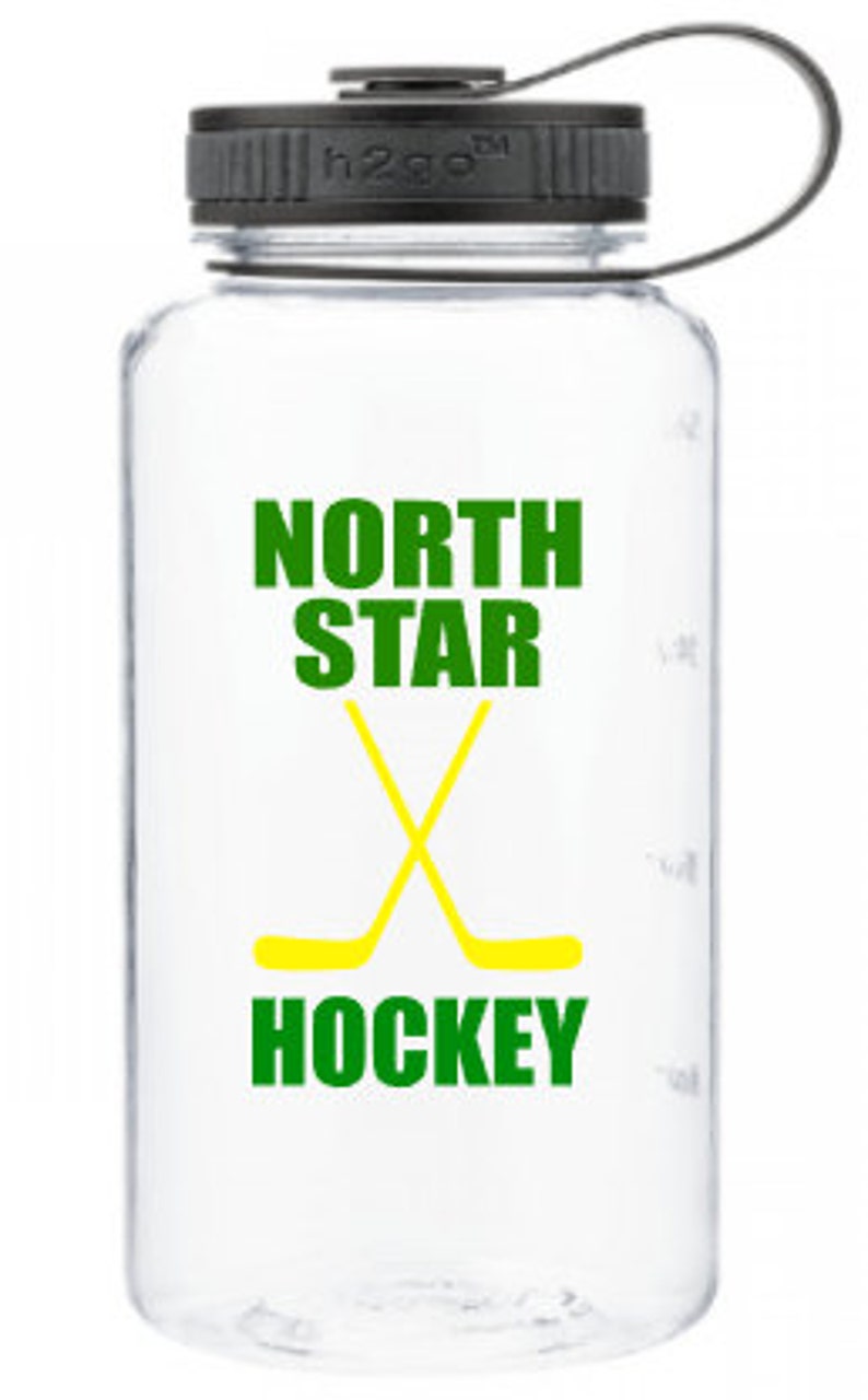 Puede incluir: Una botella de agua de pl&aacute;stico transparente con una tapa negra y un dise&ntilde;o verde y amarillo. El dise&ntilde;o dice "North Star Hockey" con dos palos de hockey cruzados.