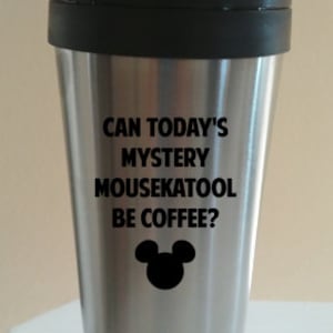 May include: A silver travel mug with a black lid and a black Mickey Mouse silhouette. The mug has the text "Can today's mystery mousekatool be coffee?" printed on it.