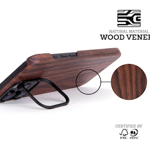 May include: A brown wood phone case with a black kickstand. The case is made from natural wood veneer and is certified by the FSC and PEFC. "NATURAL MATERIAL WOOD VENEER" is printed on the image.