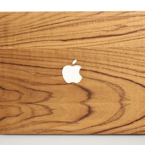 May include: A wooden laptop case with a natural wood grain finish and a white Apple logo cutout. The case has a slightly rounded edge and a subtle wood grain pattern.