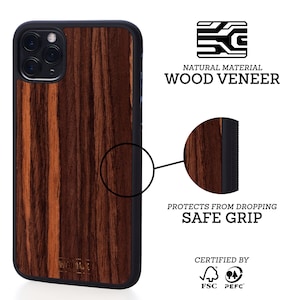 May include: A brown wood veneer iPhone case with a black border and a raised camera bump. The case has a textured surface and a safe grip. The case is certified by FSC and PEFC.