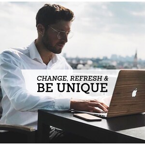 May include: A person working on a laptop computer with a wooden cover. The laptop is on a table with a smartphone. The text "CHANGE, REFRESH & BE UNIQUE" is visible on the laptop.