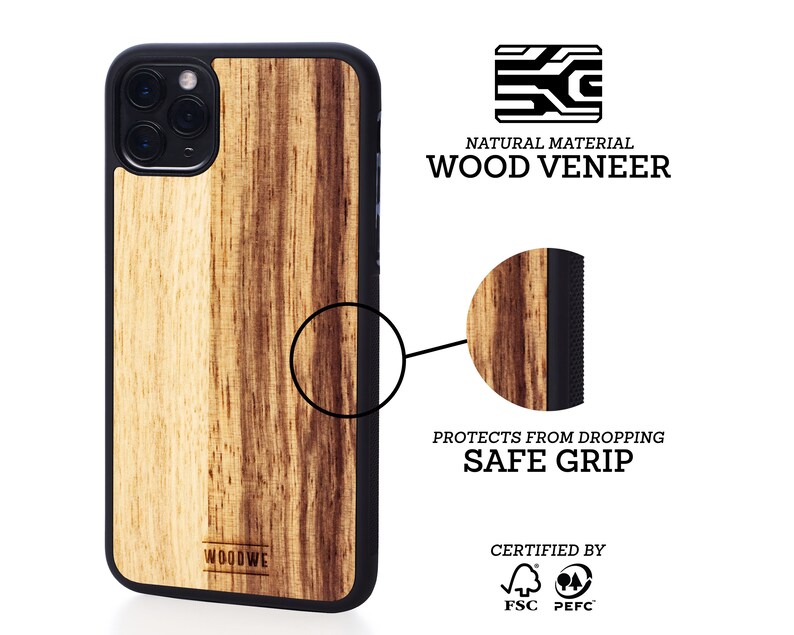 K&ouml;nnte beinhalten: Eine Handyh&uuml;lle aus Holzfurnier f&uuml;r ein iPhone mit schwarzem Gummibumper. Die H&uuml;lle hat ein nat&uuml;rliches Holzmaserungsmuster und ist FSC- und PEFC-zertifiziert. Der Text "WOODWE" ist auf der H&uuml;lle aufgedruckt. Die H&uuml;lle ist so konzipiert, dass sie das Telefon vor St&uuml;rzen sch&uuml;tzt und einen sicheren Griff bietet.