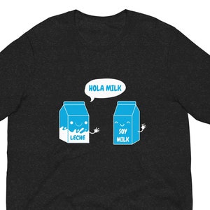 May include: A dark heather grey t-shirt with a graphic of two cartoon milk cartons. One carton says "Soy Milk" and the other says "Leche" with a speech bubble above them that says "Hola Milk".