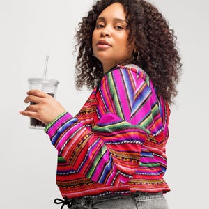 Può includere: Giacca a maniche lunghe dai colori vivaci con un motivo a righe rosse, rosa, verdi e blu. La giacca ha un cordoncino in vita ed è abbinata a jeans grigi. Le maniche e la vita hanno un design a coste.