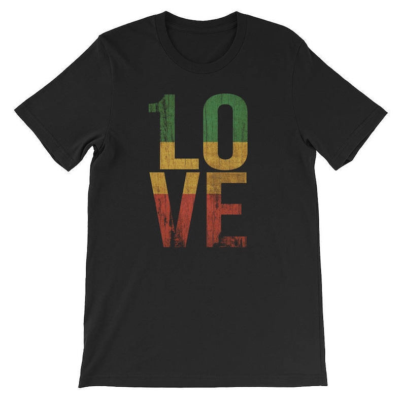 Op de afbeelding: Zwart T-shirt met het woord "LOVE" in grote, vetgedrukte letters. Elke letter is gekleurd in de kleuren rood, geel en groen van de Rastafari-vlag.