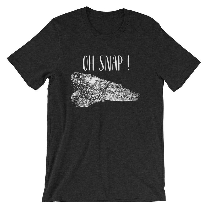 May include: A dark heather grey t-shirt with a white graphic of a crocodile and the text "OH SNAP!"
