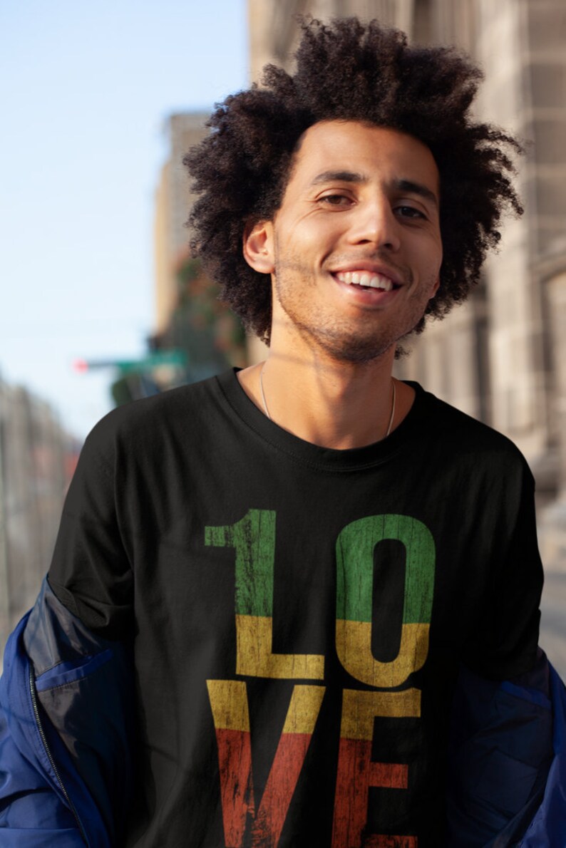 May include: A black t-shirt featuring a graphic of the word "LOVE" in red, yellow and green. The letters are styled to look like wood.